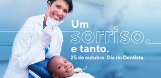 Fundo azul, com jovem dentista em pé puxando a máscara para baixo, exibindo sorriso, e jovem paciente sentado na cadeira de dentista sorrindo.