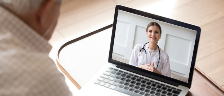 Paciente idoso em frente ao notebook, realizando consulta por telemedicina