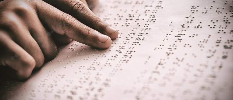 Dois dedos indicadores fazendo leitura de texto em braille