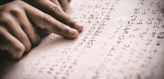 Dois dedos indicadores fazendo leitura de texto em braille