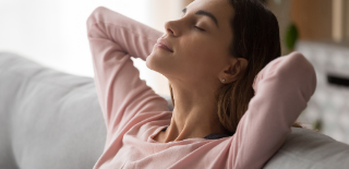 Mulher sentada no sofá com olhos fechados relaxando