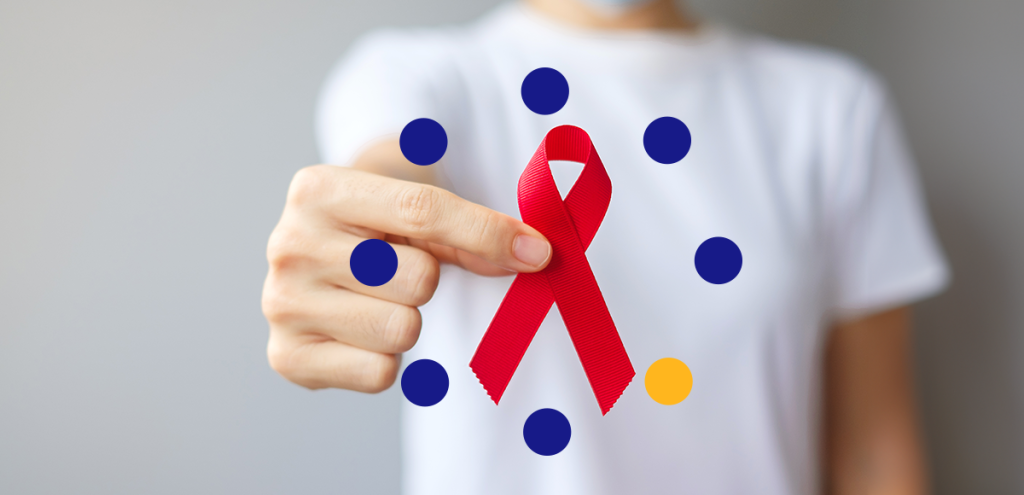 uma mão segurando uma fita vermelha, simbolizando o dezembro vermelho. Prevenção contra o HIV/ AIDS