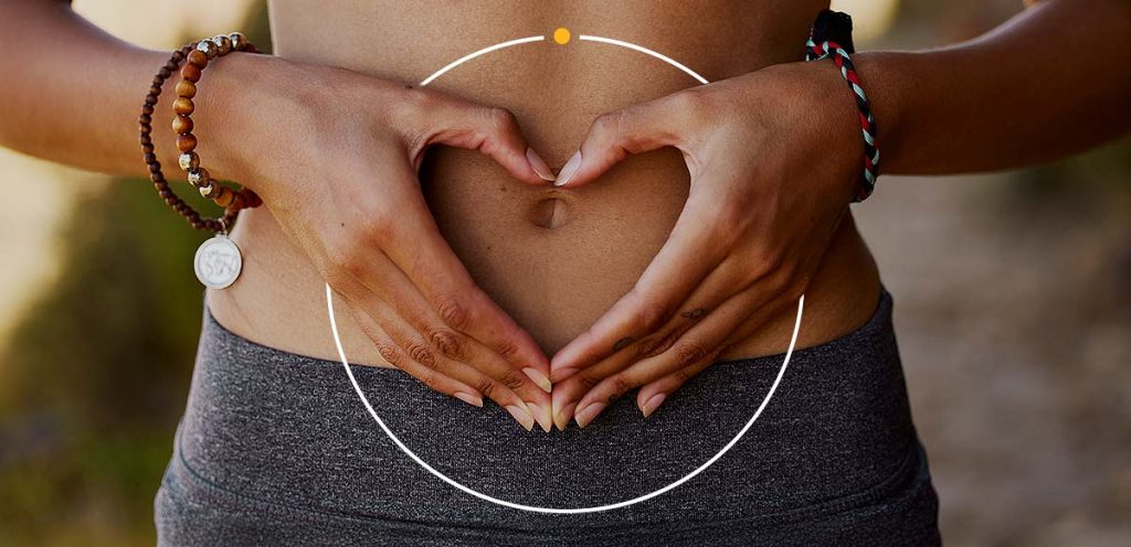 Imagem de uma mulher com as mãos na barriga em formato de coração, simbolizando Endometriose principais sintomas, causas e tratamentos