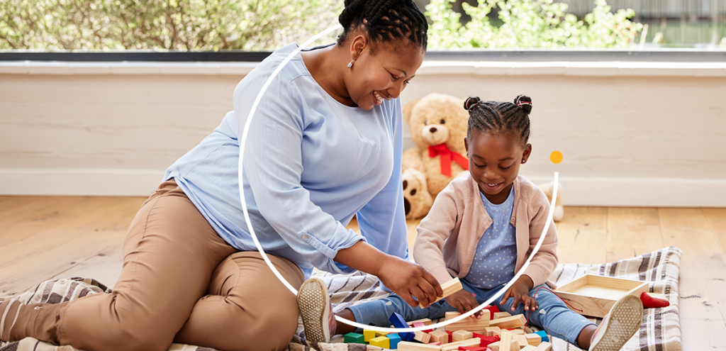 Cuidadora brinca com criança em atividade lúdica no chão, simbolizando apoio ao desenvolvimento infantil e conscientização sobre o autismo no Abril Azul.