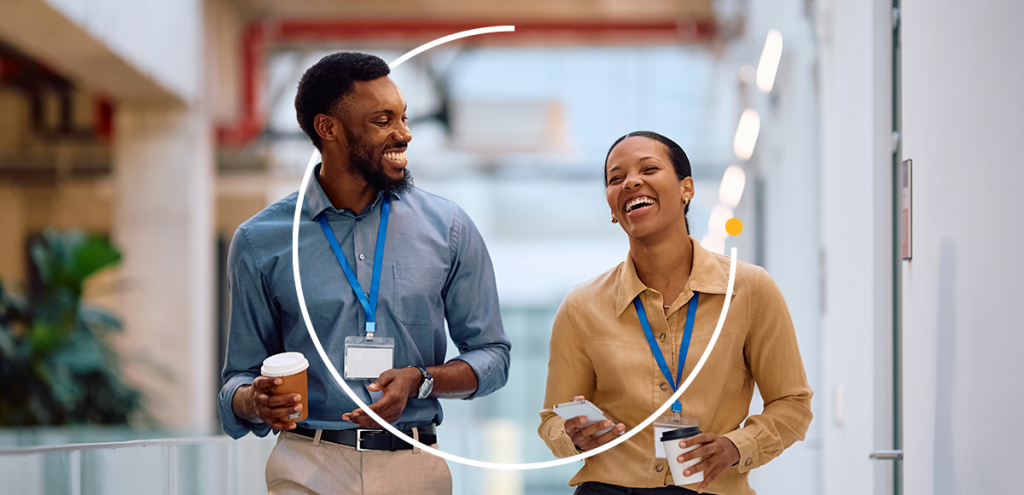 Colaboradores conversam no ambiente de trabalho, representando a campanha Abril Verde de saúde e segurança no trabalho, prevenção de acidentes e cuidado com o bem-estar físico e mental dos trabalhadores no Brasil.