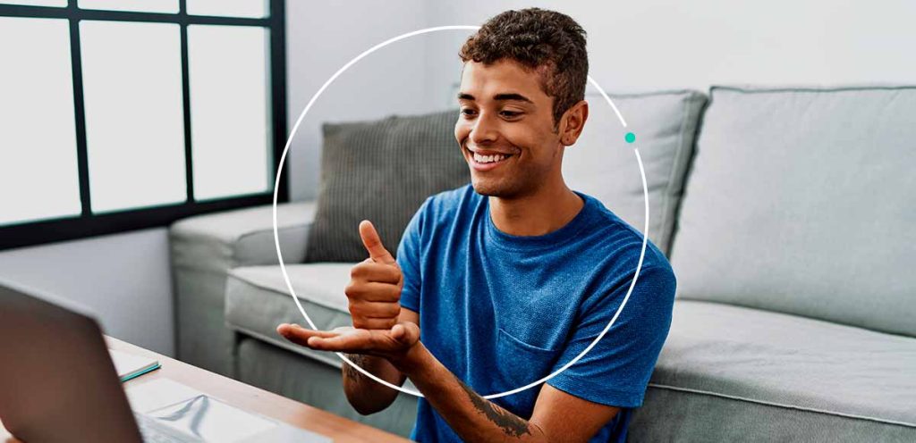 Imagem de um jovem fazendo sinais em frente uma tela de computador, simbolizando o dia nacional do surdo