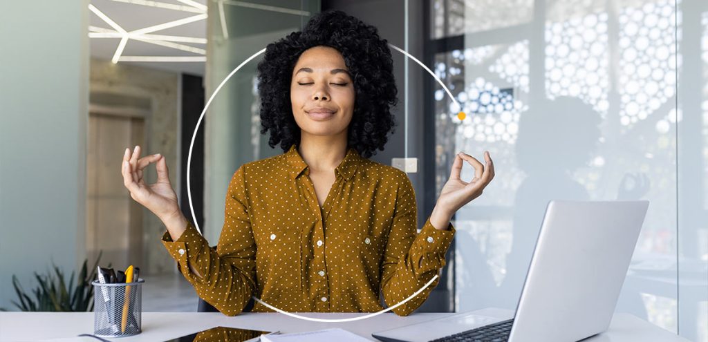 Imagem de uma moça meditando a frente de um notebook, simbolizando cuidados essenciais para a saúde mental no ambiente de trabalho